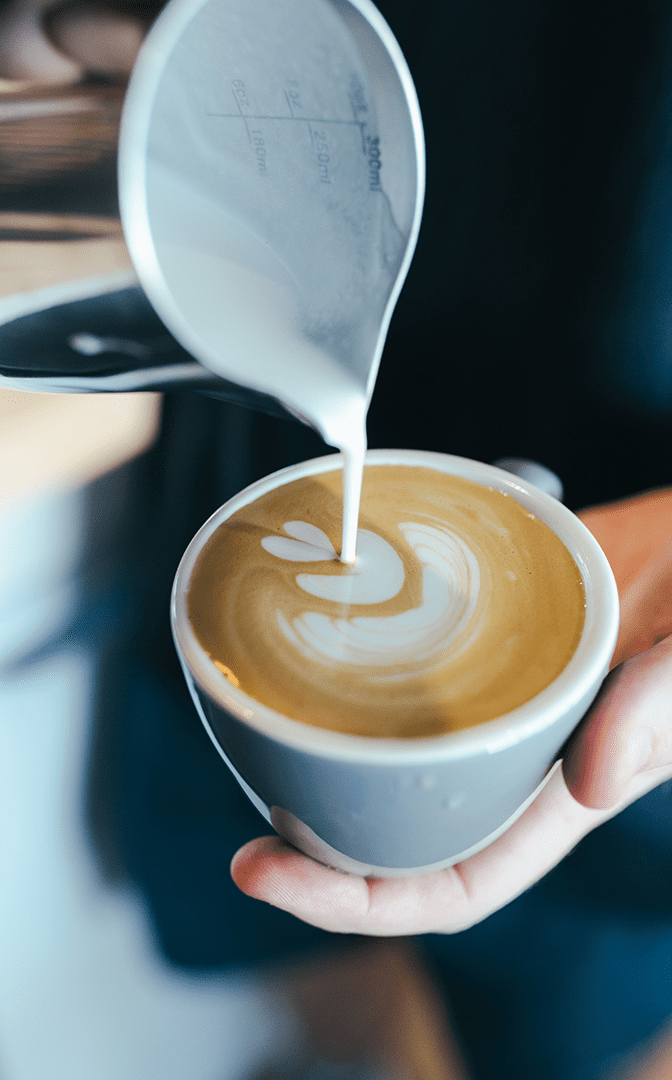 A Perth Coffee Roaster pouring latte art into a mug.